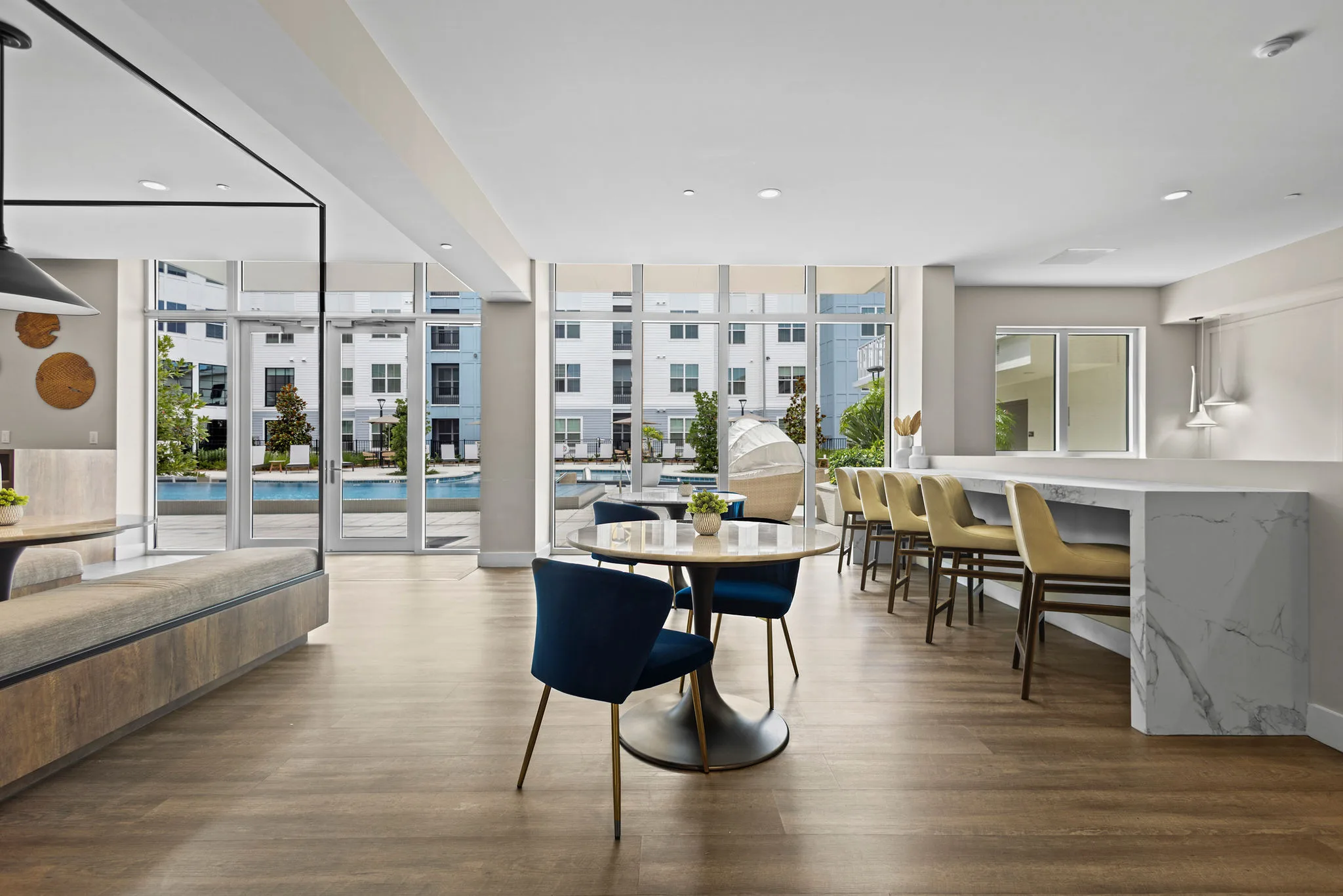 Clubroom lounge at WaterView Echelon City Center in St. Petersburg, FL, with marble bar counter, dining seating, & floor-to-ceiling windows overlooking the pool