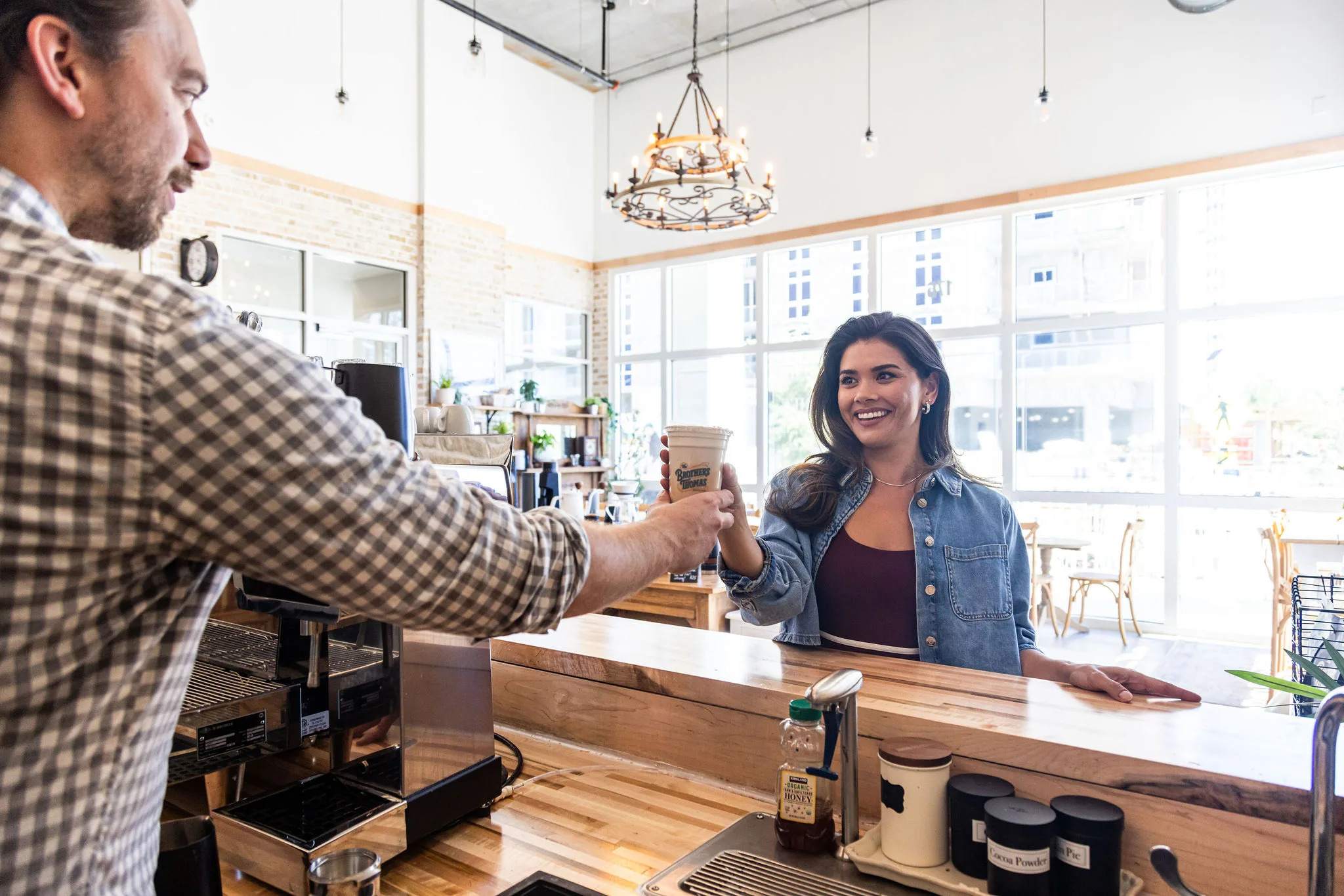Barista handing a smiling woman a coffee drink at a coffee shop